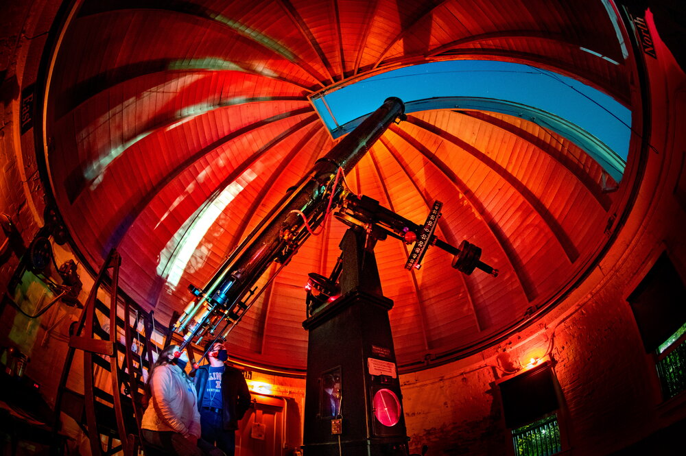 A pair of people looking into a telescope in an observatory.