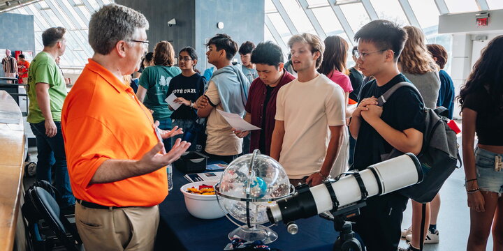 A person in a booth talks to students interested in astronomy.