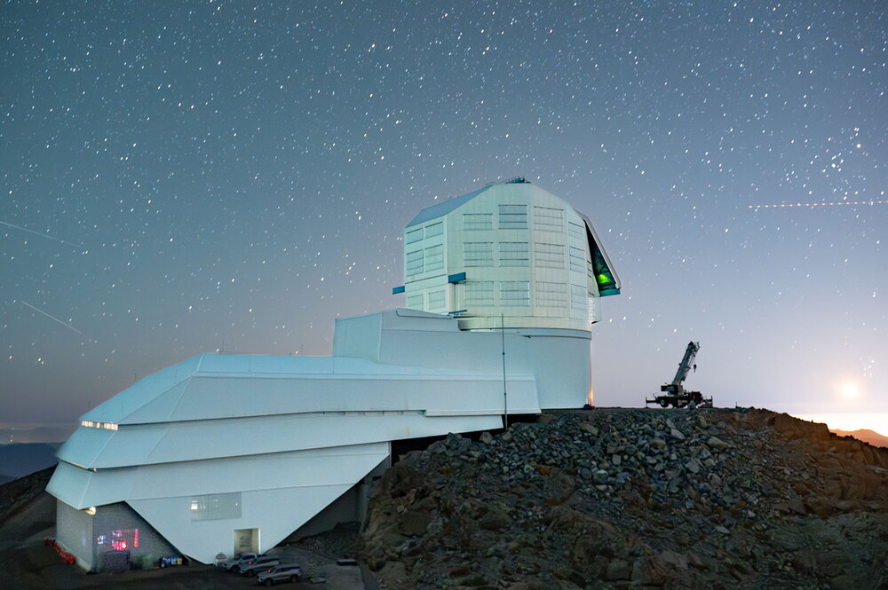 An observatory in front of a night sky in the desert.