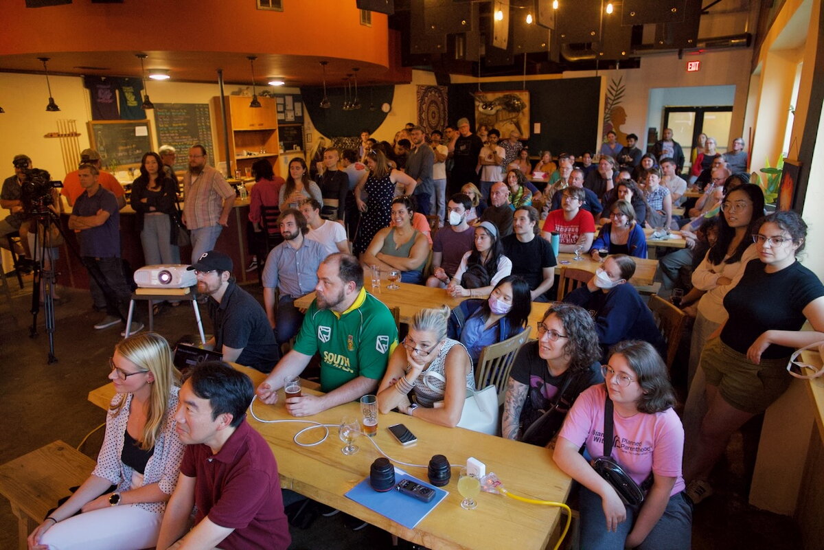 General public attending an Astronomy on Tap event, looking at an off-screen speaker.