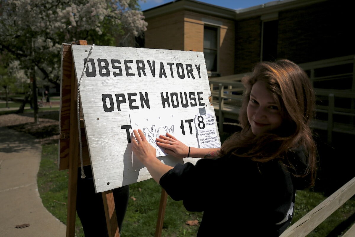 A student setting up a sign board to announce the Observatory Open Night