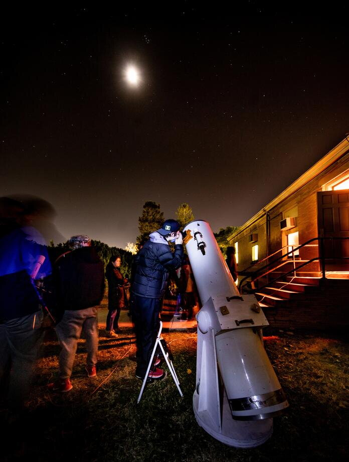 Student looking at the moon through a telescope