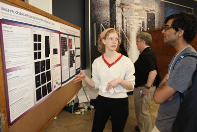 A student presenting a poster to another student.