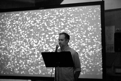 Joaquin Vieira talks in front of a projection screen for Astronomy On Tap.