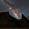 A picture of stars in the sky over a dark rock formation.