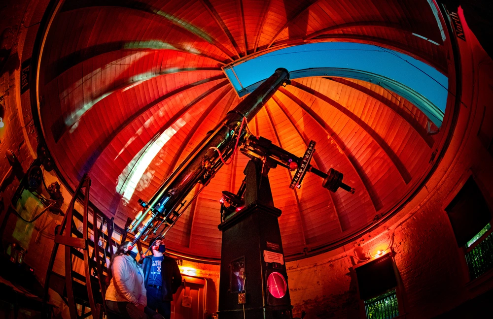 A pair of people looking into a telescope in an observatory.