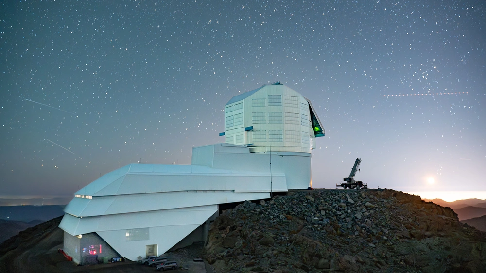 An observatory in front of a night sky in the desert.
