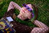 A person laying in the grass with their arms behind their head wearing solar eclipse glasses.