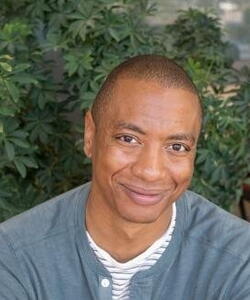 Kirk Barrow, A man in a sweater posing in front of some plants.